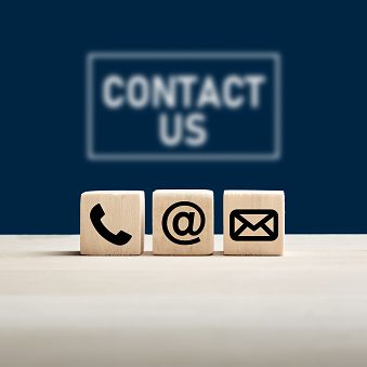 Phone and e-mail icons on wooden cubes with contact us text on blue background. Website page contact us or e-mail marketing concept.
